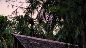 A thatched-roof structure with a staircase leading to a balcony, surrounded by tropical vegetation. - Sangat Island Dive Resort (Coron)