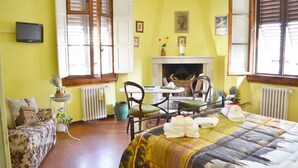 Une pièce comprenant un lit, un canapé, une table à manger avec des chaises, une cheminée et un téléviseur fixé au mur.