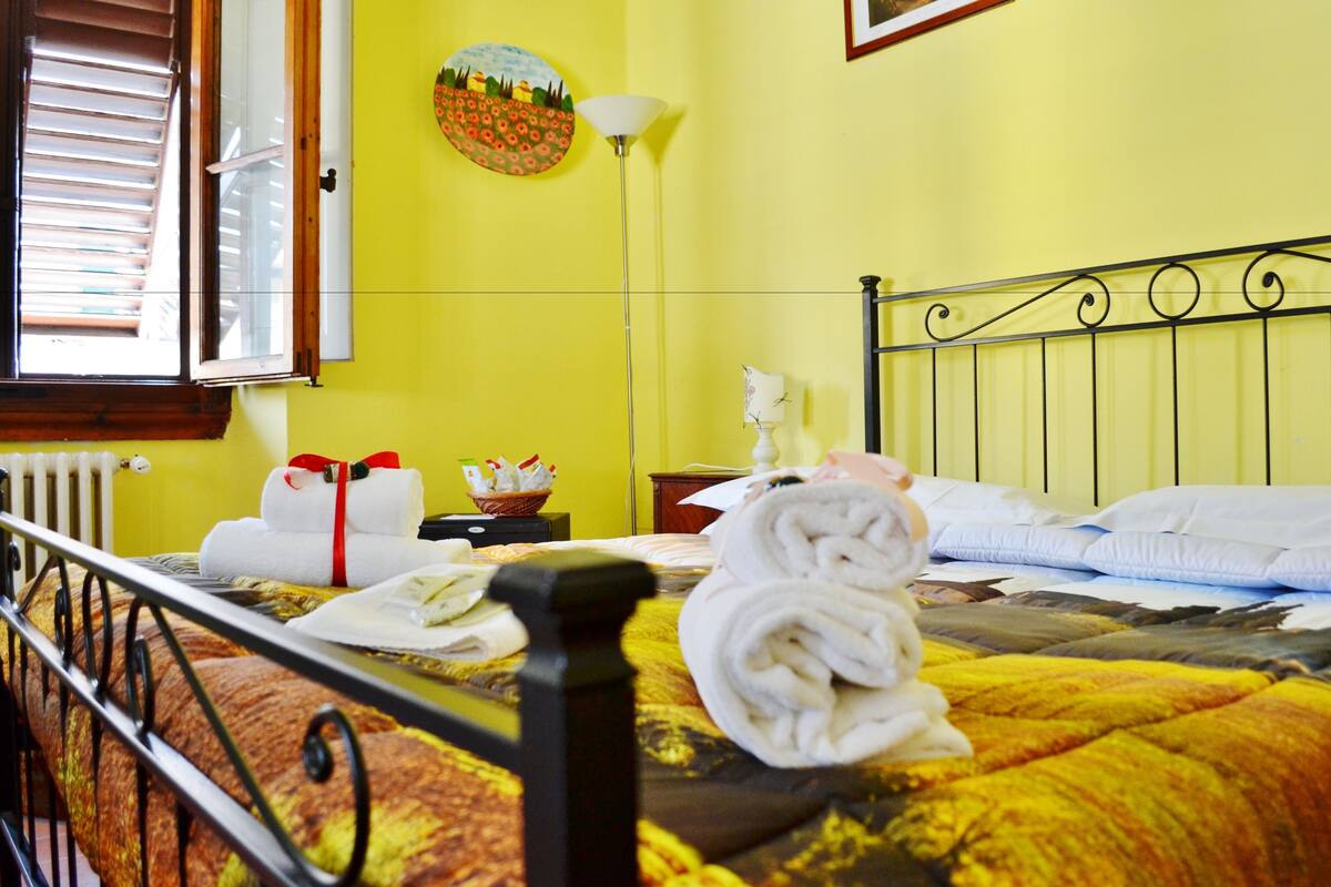 Een hotelkamer met een bed, handdoeken, een lamp en een raam met jaloezieën.