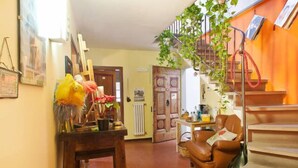 Un salon chaleureux avec un canapé en cuir marron, une table basse en bois et un escalier doté d’une rampe en corde rouge.