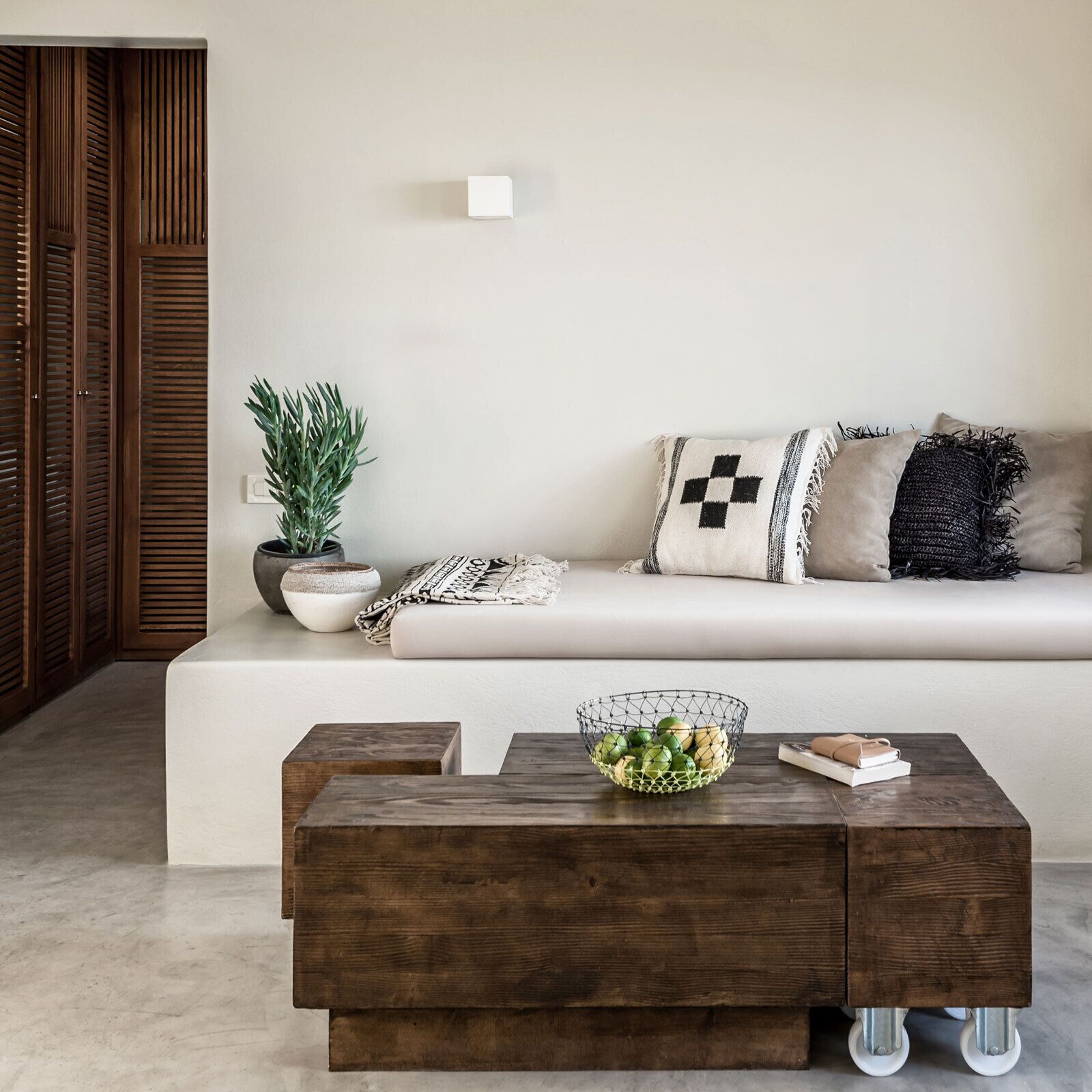 En moderne stue med en sofa, et træ sofabord, en potteplante og en vægmonteret lampe.