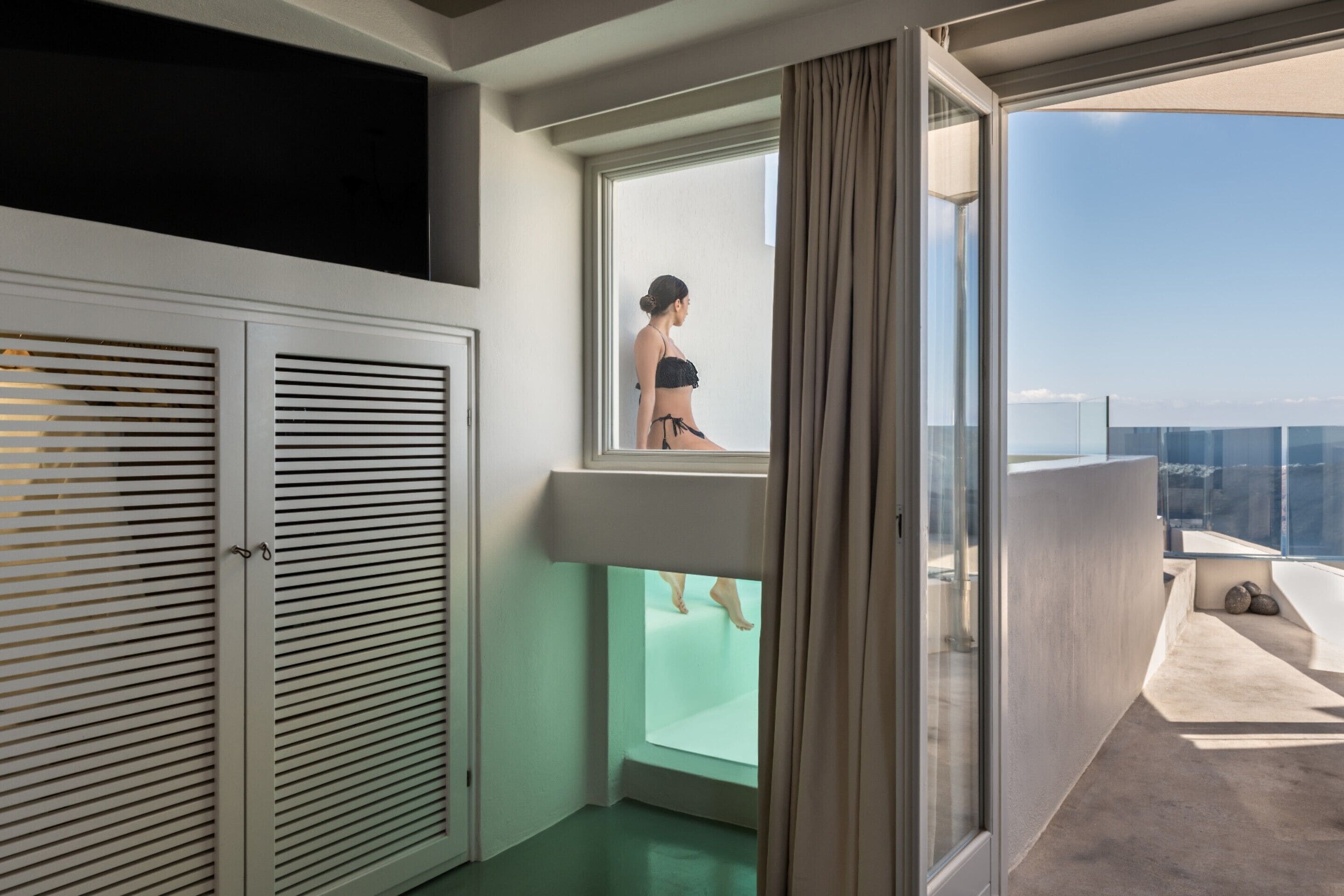 Una habitación moderna con balcón acristalado, bañera y armario.