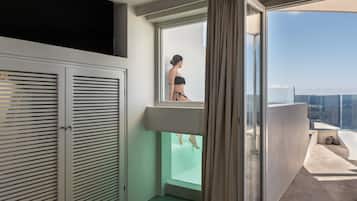 Una habitación moderna con balcón acristalado, bañera y armario.