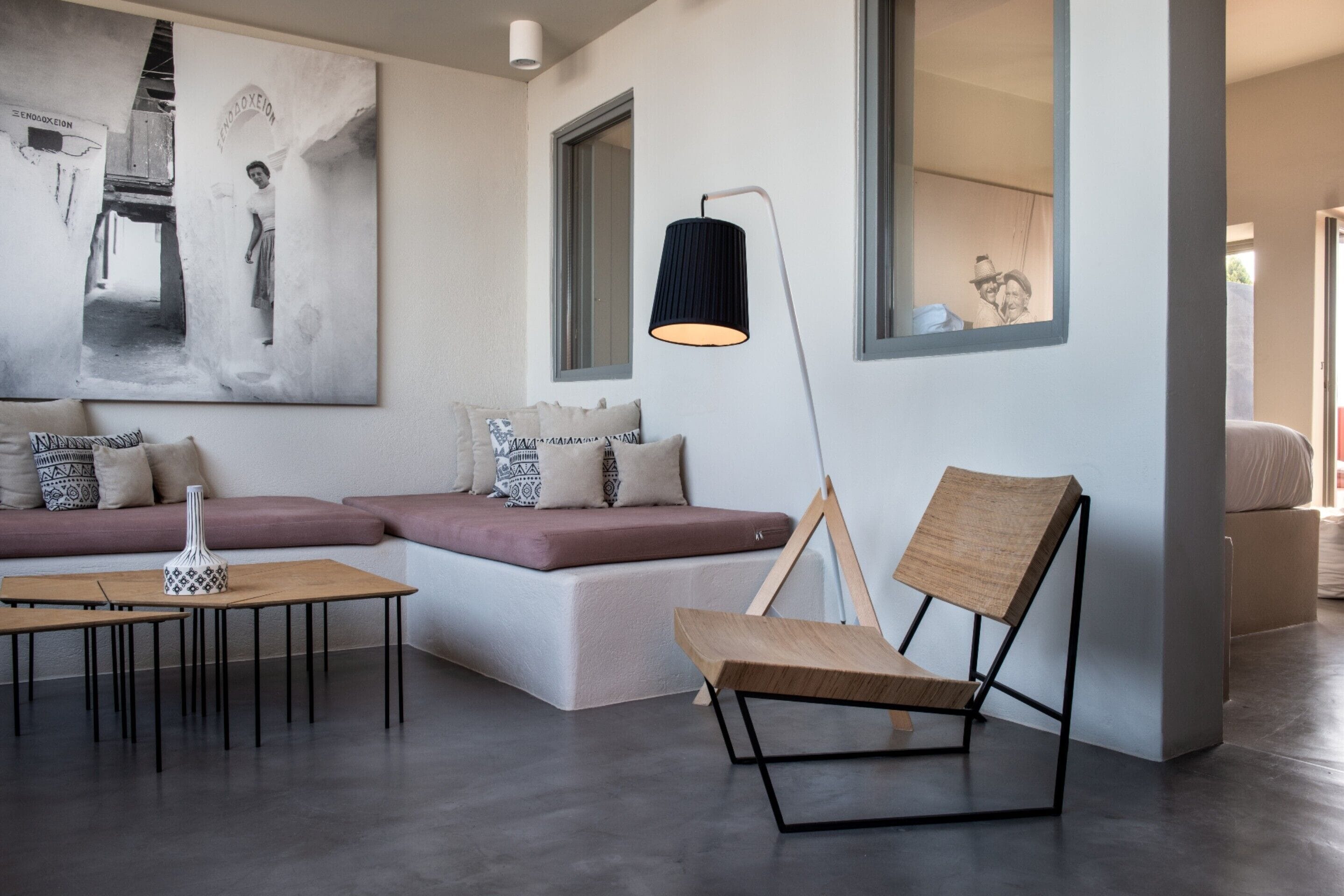 A modern living room with a sectional sofa, a wooden chair, a floor lamp, and a large abstract painting.