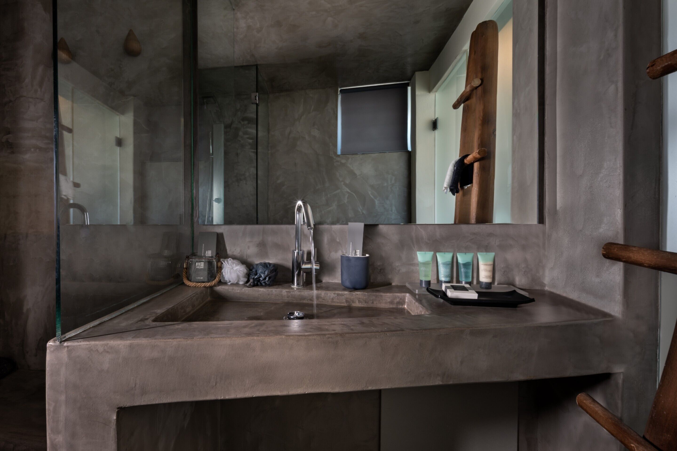 Un baño moderno con un espejo grande, un lavamanos y artículos de aseo.