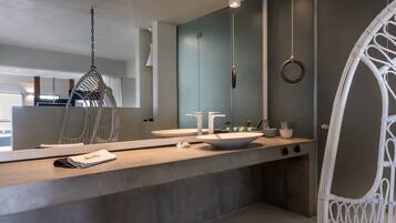 A modern bathroom with a large mirror, two sinks, a hanging chair, and a ring light.