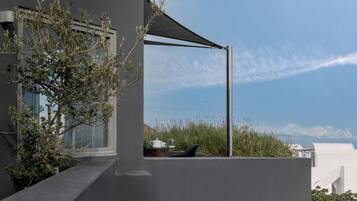 A modern building with a balcony, a table with a cup and glass, and a view of the sky and distant landscape.