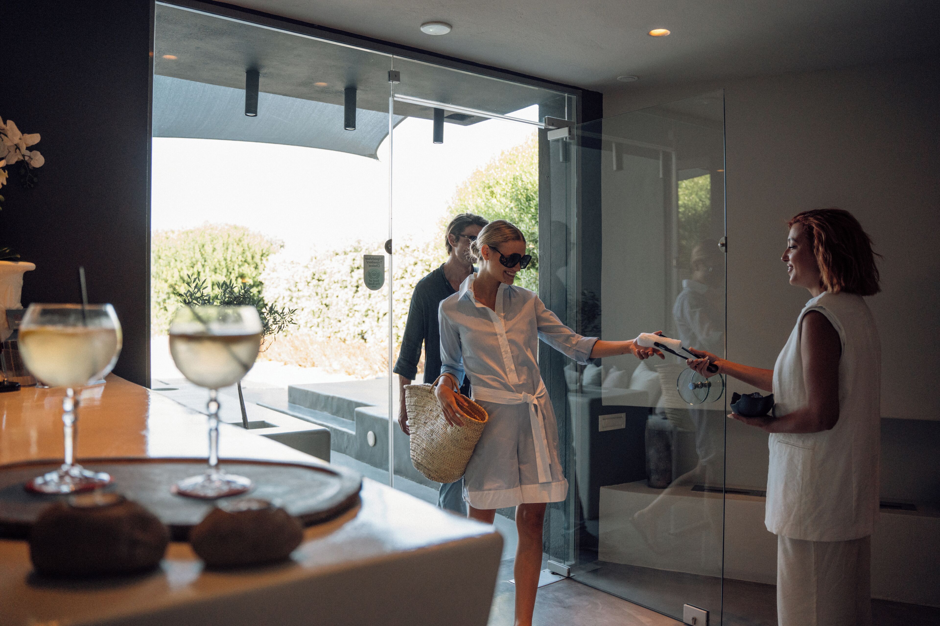 Un intérieur moderne avec une porte vitrée donnant sur un espace extérieur, une table avec des verres à vin et un panier.