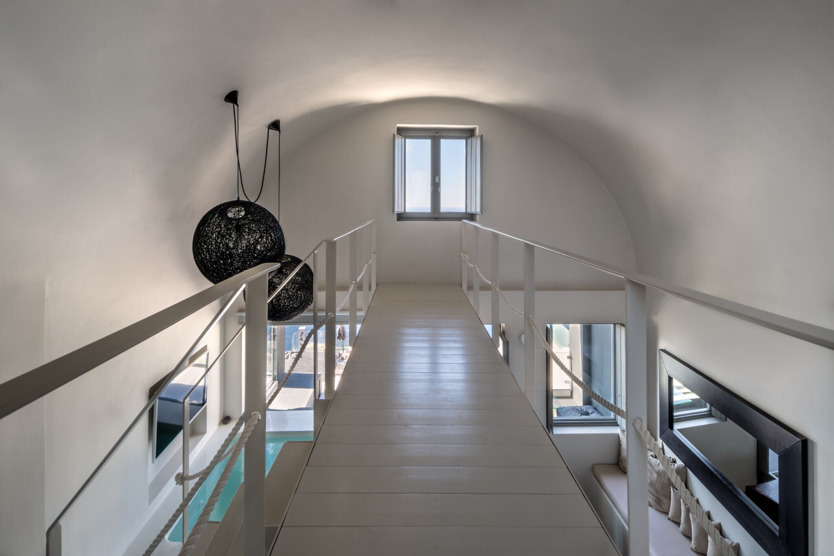 A long, narrow hallway with white railings and a sloped ceiling.