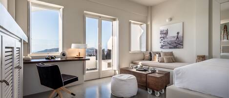 Una habitación de hotel moderna con una cama grande, un escritorio con una silla, una mesita y un ventanal con vistas al exterior.