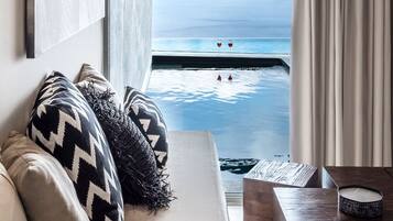 Una habitación con vista a una piscina y montañas, un sofá con cojines estampados y una mesita de madera con una vela.