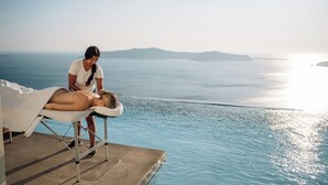 Una persona recibe un masaje junto a una piscina con vista al mar.