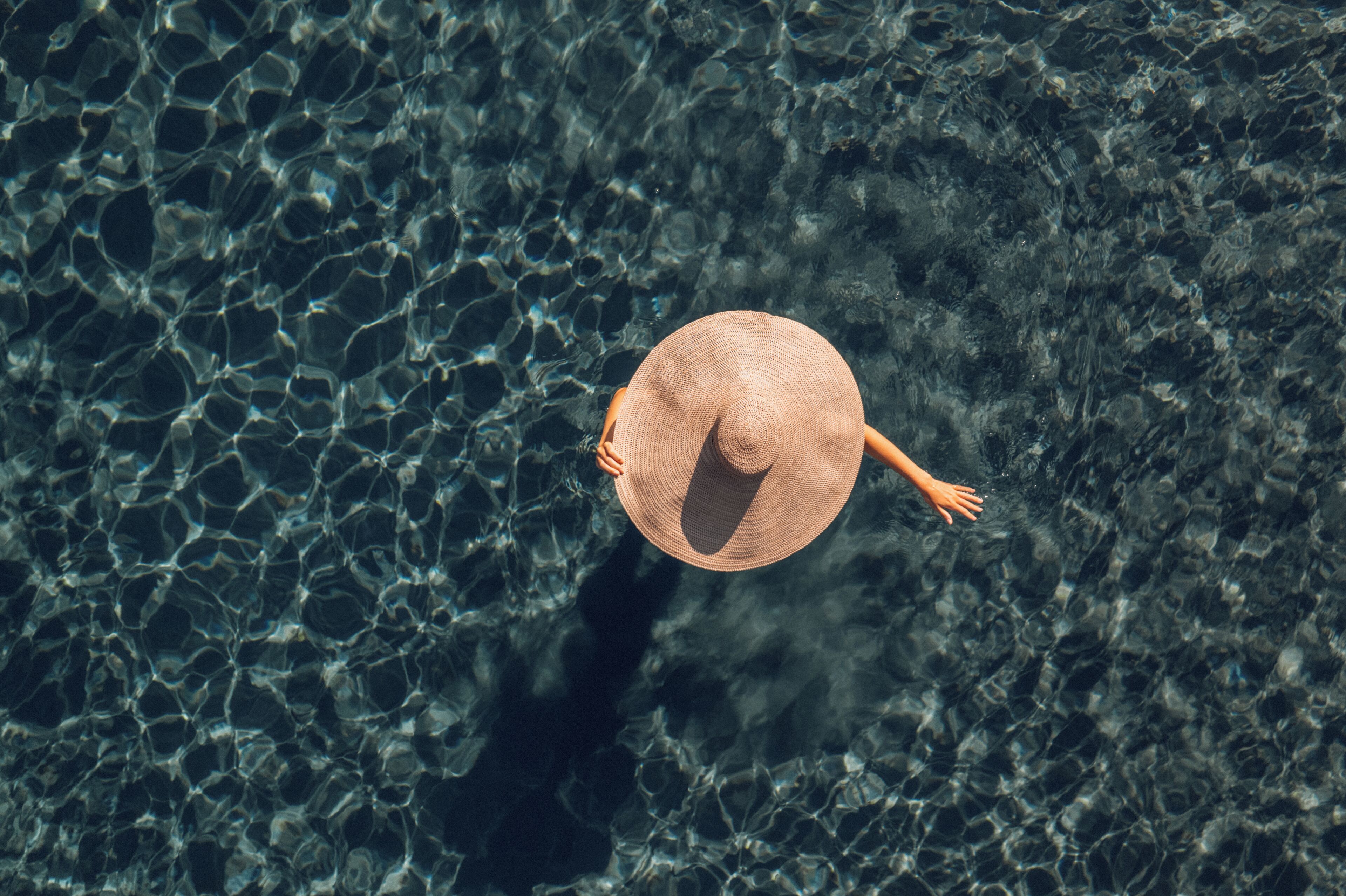 A person wearing a straw hat standing in clear water.