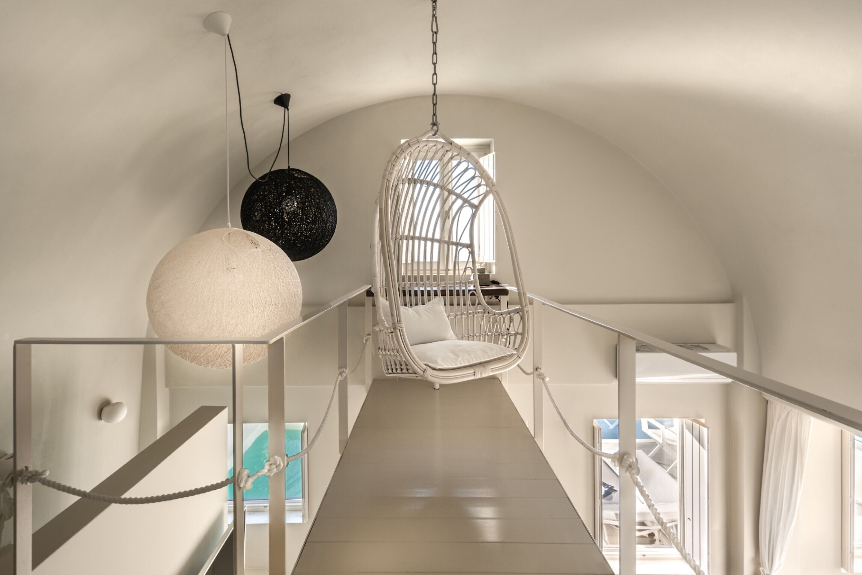 A staircase with a hanging chair and pendant light.