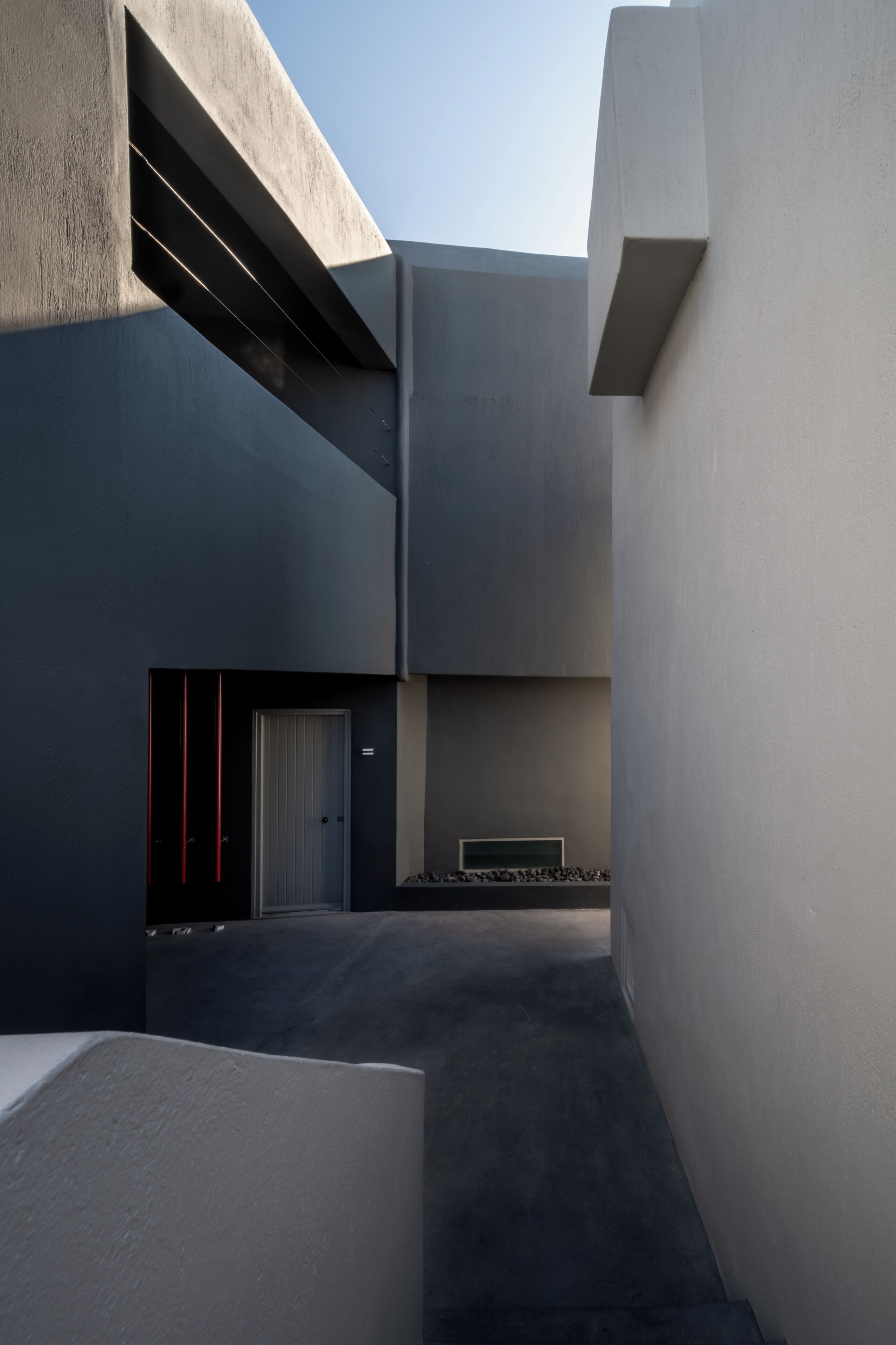 A modern architectural structure with a courtyard, a door, and a bench.