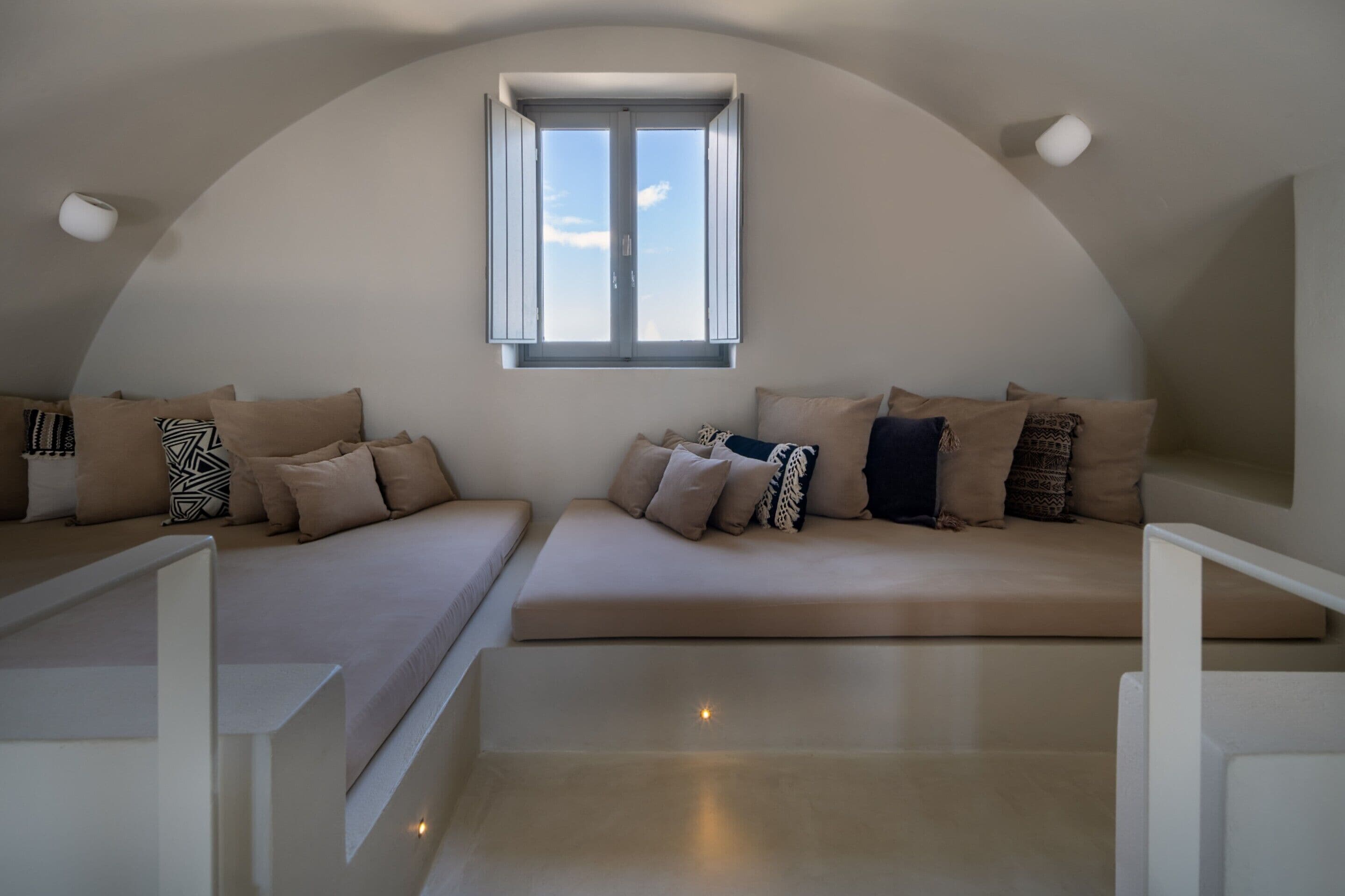 Une chambre de style loft moderne, dotée d’un plafond incurvé, d’une grande verrière et d’un canapé intégré agrémenté de plusieurs coussins.