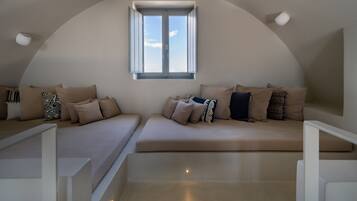 Une chambre de style loft moderne, dotée d’un plafond incurvé, d’une grande verrière et d’un canapé intégré agrémenté de plusieurs coussins.