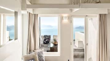 A modern living room with a sofa, a round wooden coffee table, and a view of the sea through large windows.