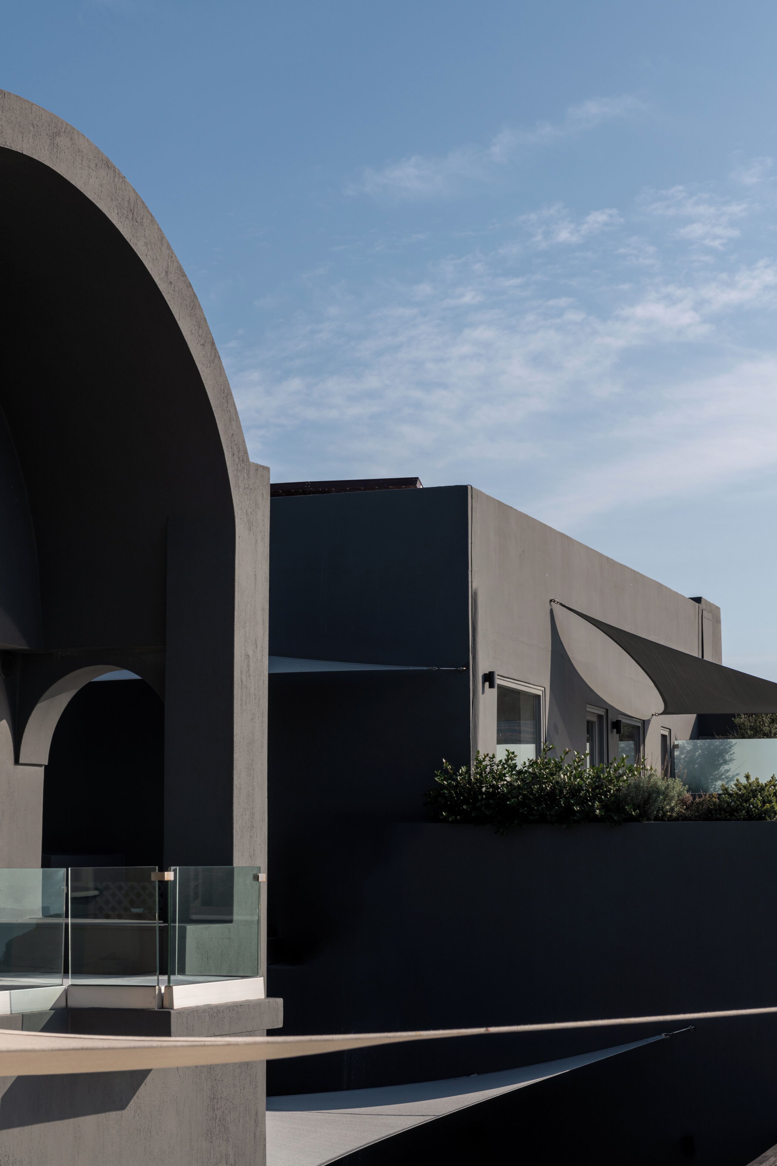 A modern building with a curved glass balcony, a flat roof, and a minimalist design.