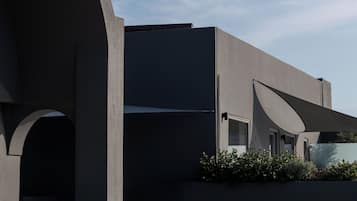A modern building with a curved glass balcony, a flat roof, and a minimalist design.