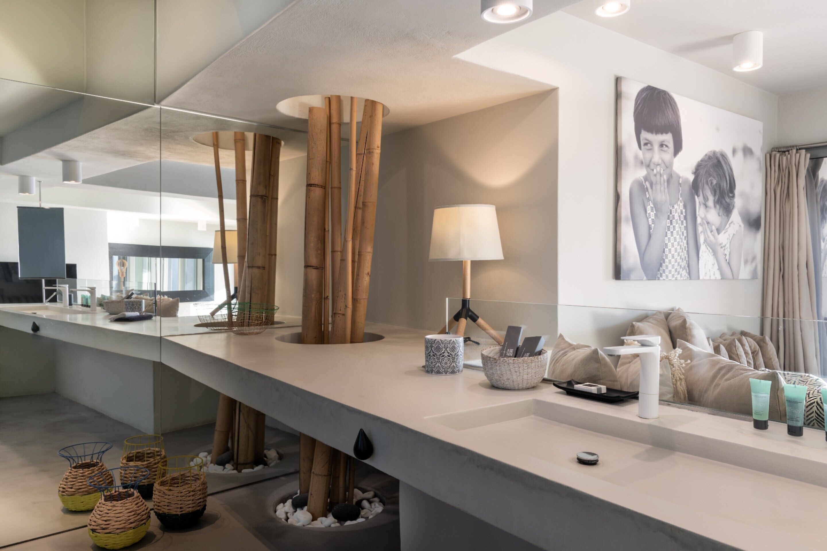 Une salle de bain moderne avec un grand miroir, une décoration en bambou, un lavabo blanc et un porte-serviettes.