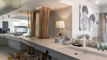 Une salle de bain moderne avec un grand miroir, une décoration en bambou, un lavabo blanc et un porte-serviettes.