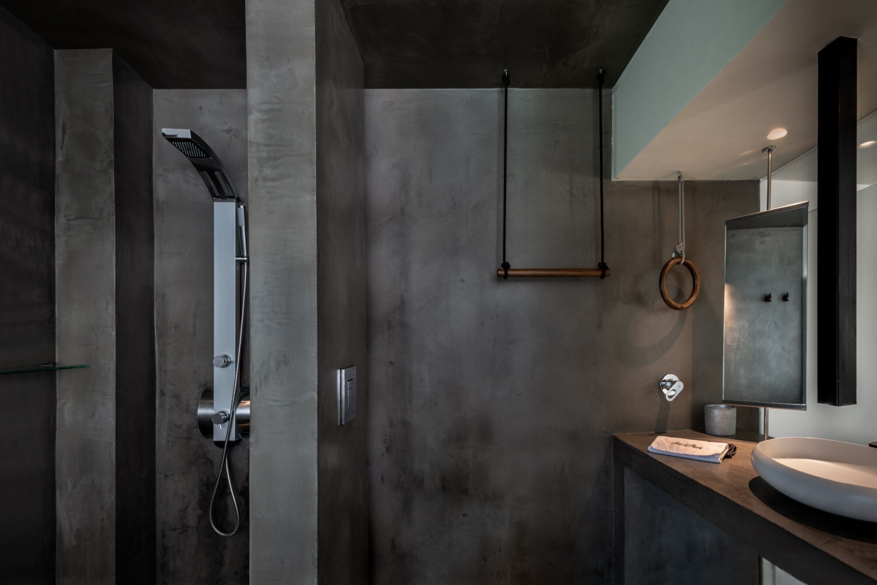 A modern bathroom with a large mirror, a round sink, and a shower with a handheld showerhead.
