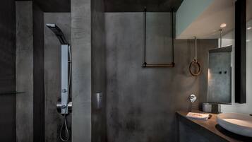 A modern bathroom with a large mirror, a round sink, and a shower with a handheld showerhead.