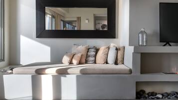 Un salon moderne avec un canapé, un grand miroir, un téléviseur et une bouteille décorative.