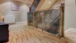 Ein Zimmer mit einem gemusterten Teppich, einer Treppe mit Glastrennwand und einem Heizkörper.