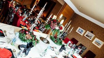 A dining area with tables set for a meal, featuring floral centerpieces and candles.