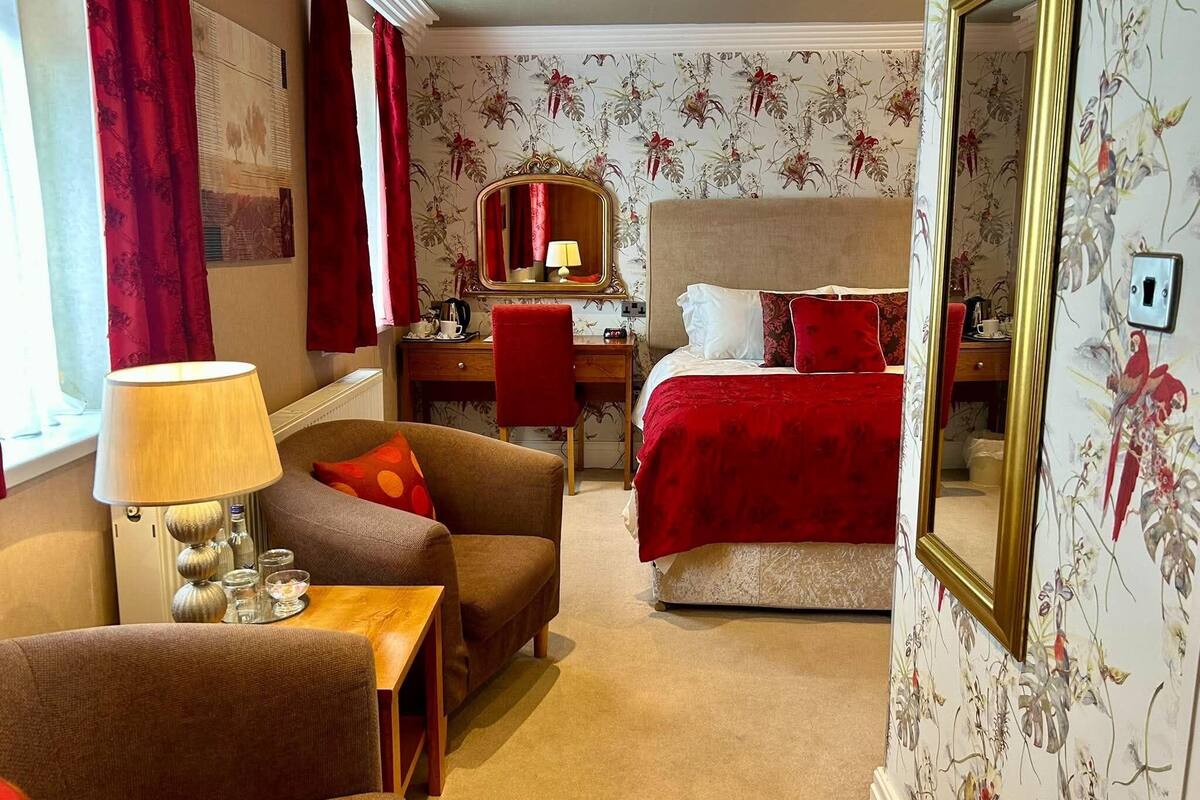 Une chambre d’hôtel comprenant un lit, un bureau avec une chaise, un canapé, une lampe et un miroir.