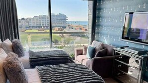 Ein Hotelzimmer mit zwei Betten, einem Fernseher und Blick auf Gebäude und Grünflächen.