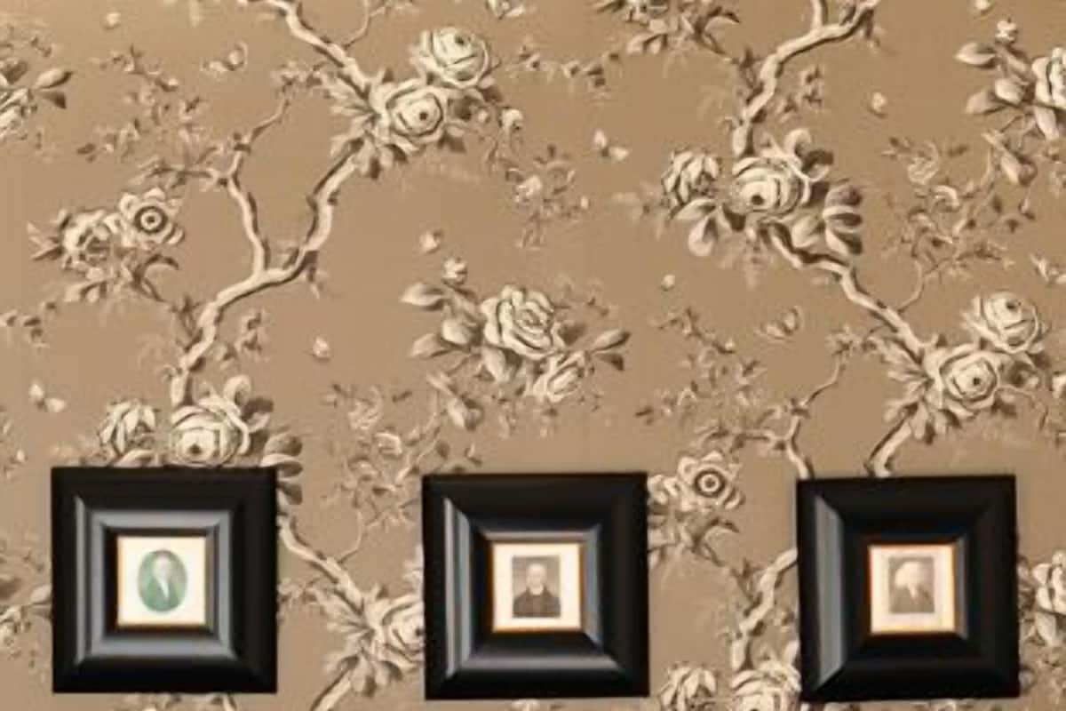 A wall with a floral pattern and three framed pictures.