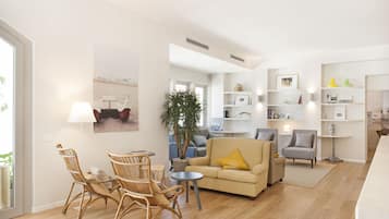 Relax in a cozy seating area with a sofa, armchair, and small table, surrounded by a large potted plant and decorative items.