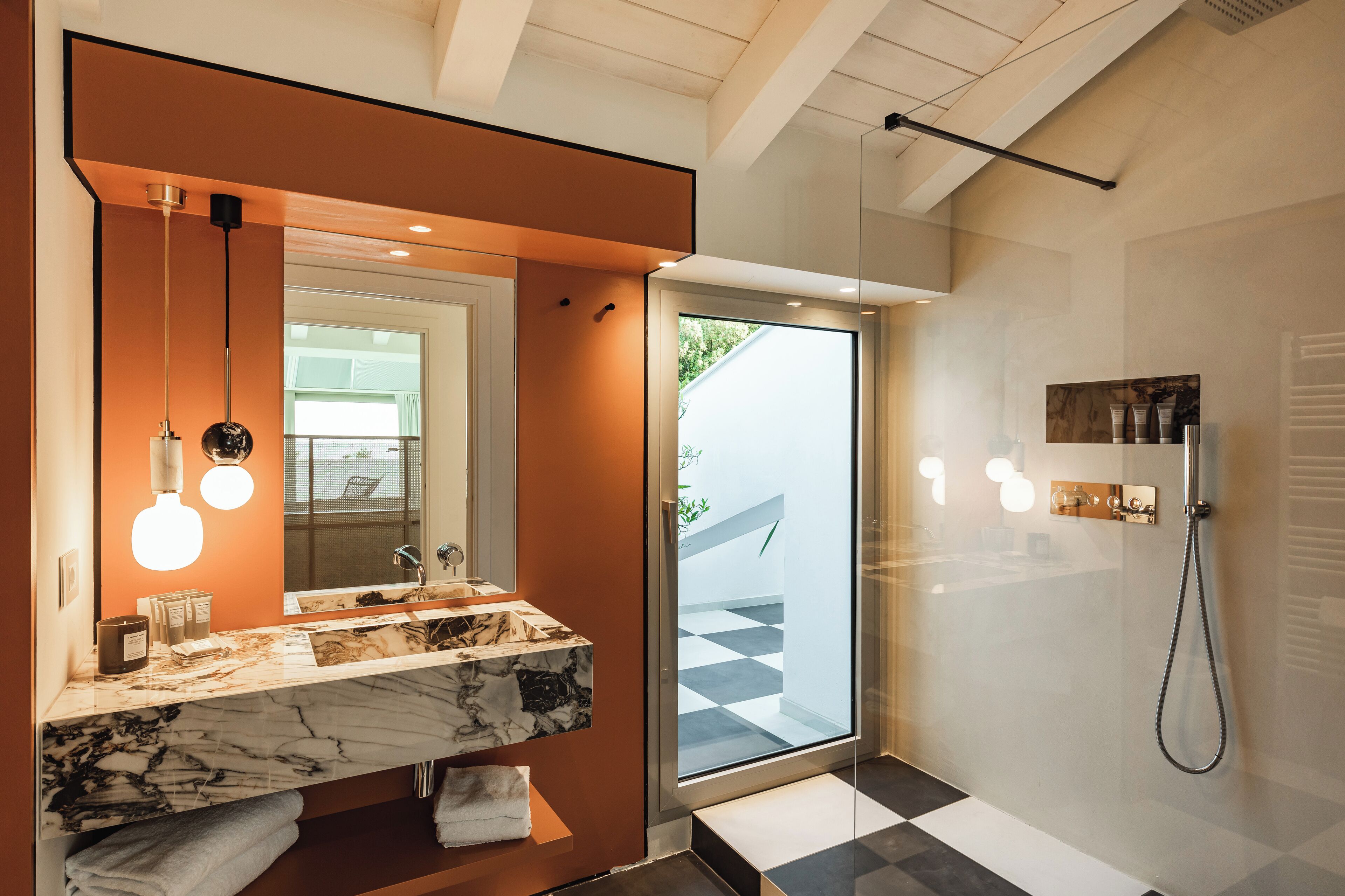 A modern bathroom with a marble sink, a large mirror, and a glass shower enclosure.