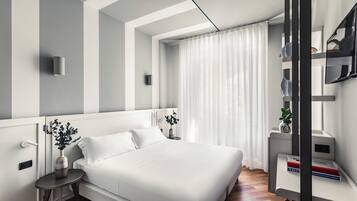 Een moderne slaapkamer met een groot bed, nachtkastjes, een klein bijzettafeltje met een vaas, en een inbouwkast voor de televisie.