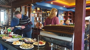A buffet setup with various dishes and a piano in the background. - Sapa House Hotel Halal Certified (Sa Pa)