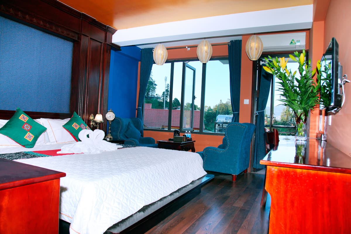A hotel room with a large bed, a desk, a chair, and a TV.