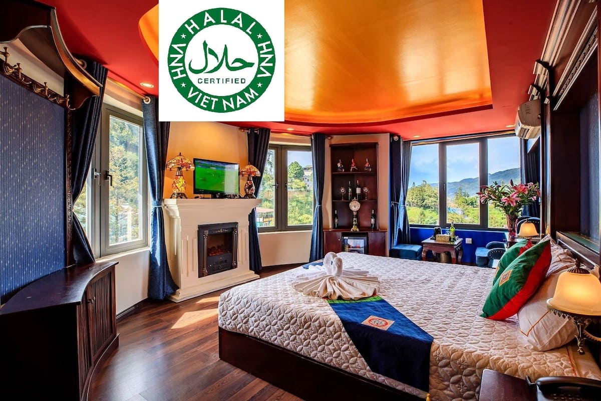 A hotel room with a large bed, a fireplace, a TV, and a view of the outdoors.