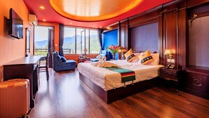 A hotel room with a large bed, a desk, a chair, and a view of mountains. - Sapa House Hotel Halal Certified (Sa Pa)