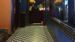 A hallway with a checkered floor, a hanging light fixture, and a display of vases and flowers. - Sapa House Hotel Halal Certified (Sa Pa)