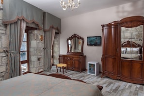 A bedroom with a large bed, a wooden dresser, a mirror, and a television.