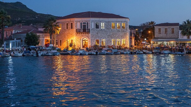 Ein Gebäude am Wasser mit mehreren Balkonen und einer Anlegestelle voller Boote.