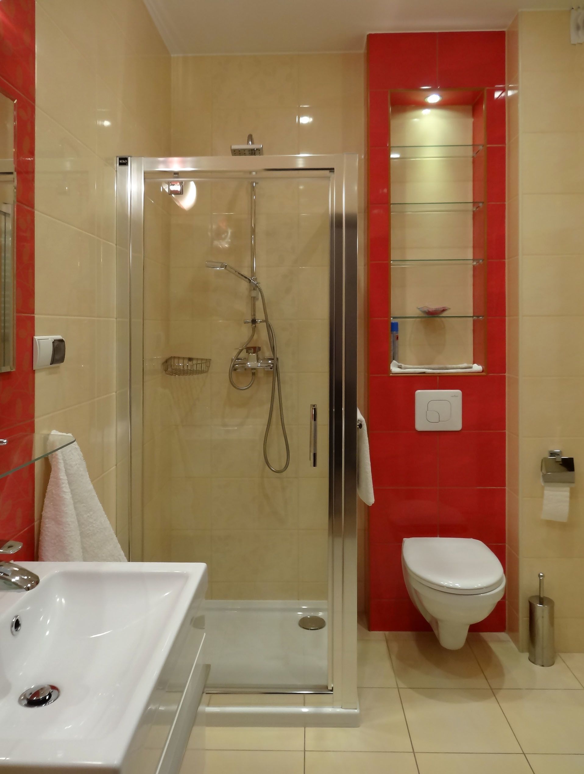 Et moderne badeværelse med en glasafskærmet brusekabine, en hvid vask og et toilet.