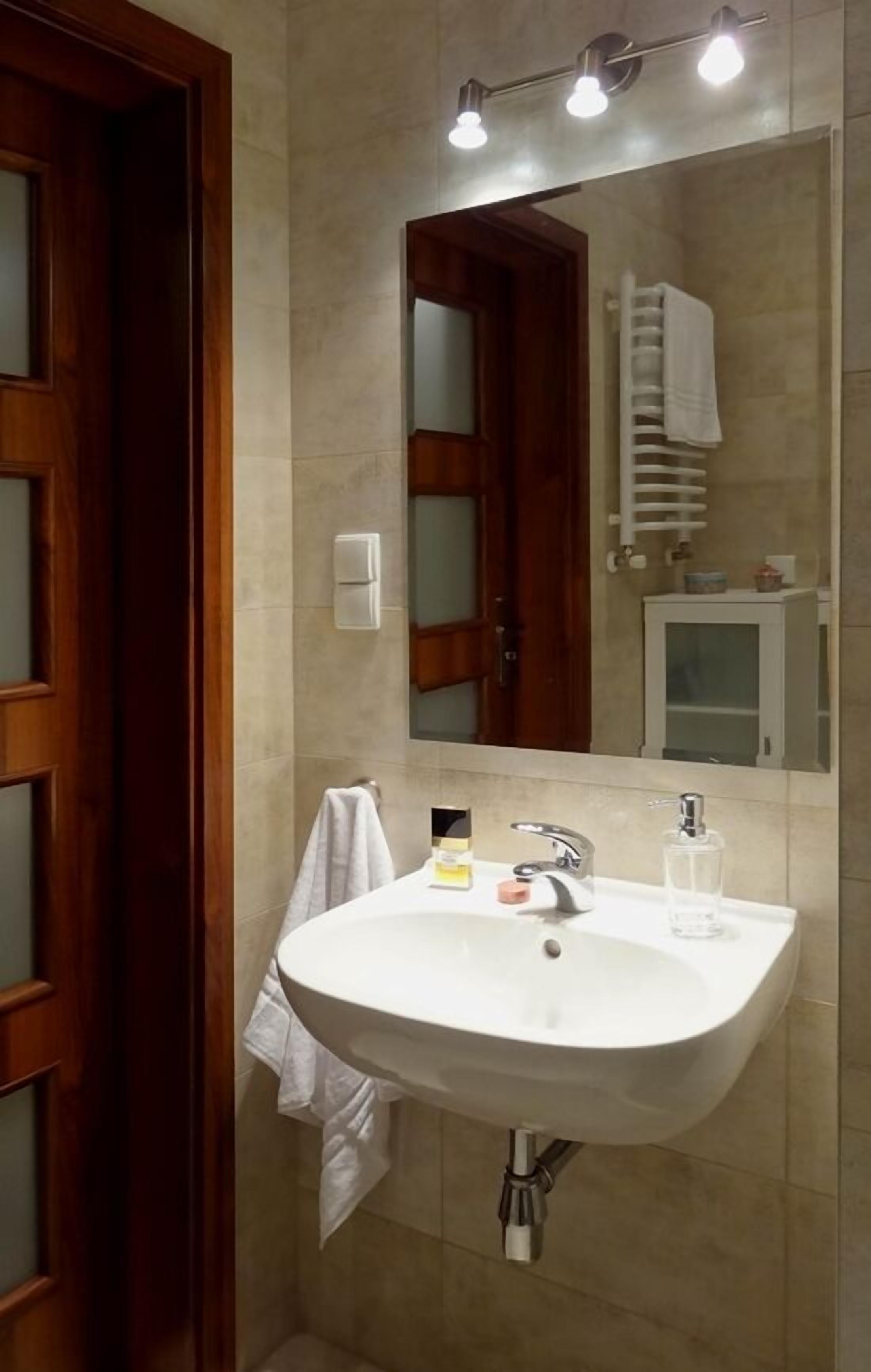 A bathroom with a white sink, a mirror, and a towel rack.