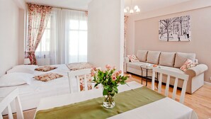 A modern living room with a sofa, a dining table, and a vase of flowers. - Apartamenty Centrum Villa Perla (Jelenia Gora)
