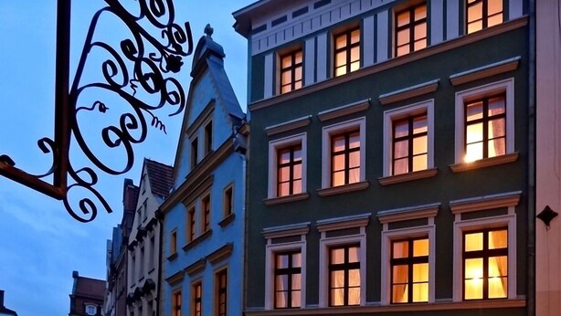 A street view of a European town with traditional architecture, including a shop with a visible sign. - Apartamenty Centrum Villa Perla (Jelenia Gora)
