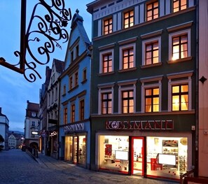 Une vue d’une rue d’une ville européenne, avec une architecture traditionnelle, notamment un magasin dont l’enseigne est bien visible.