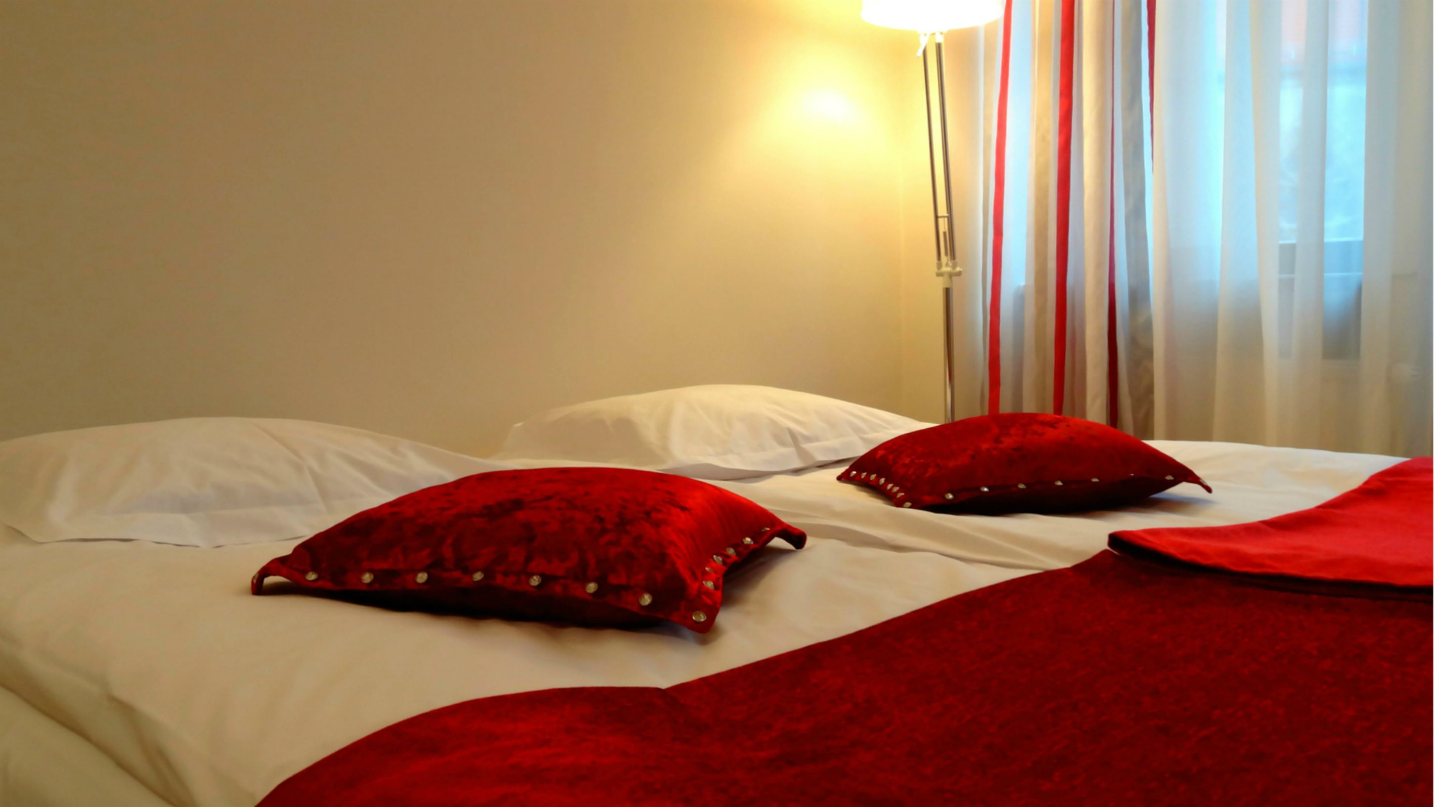 Ein Hotelzimmer mit zwei Betten, jeweils mit weißen Laken und roten Kissen.